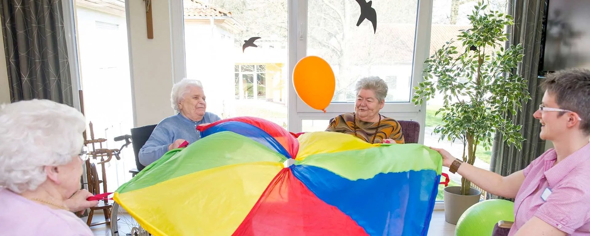 vier Frauen "balancieren" einen Luftballon mit Hilfe eines großen Tuchs, das sie gemeinsam halten